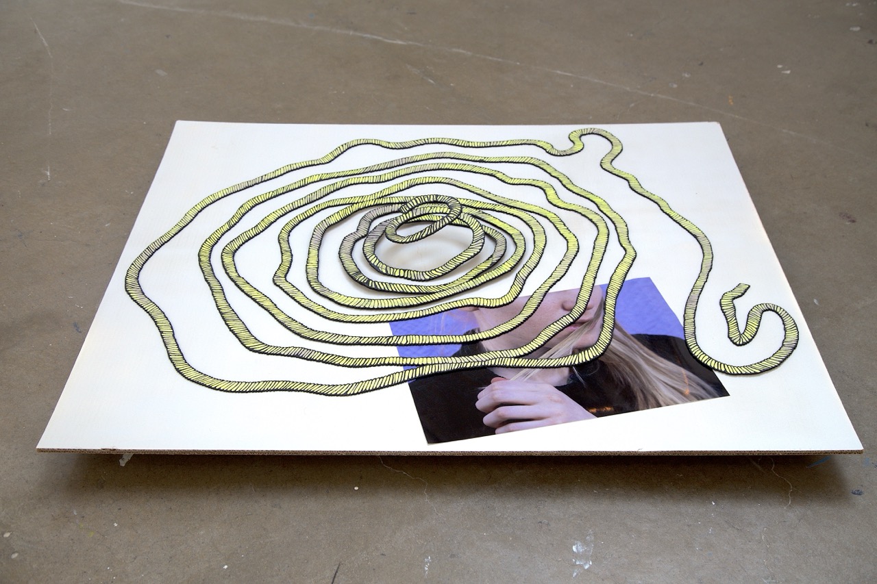 fake rope, coiled on a platform, partially covering an image of a woman